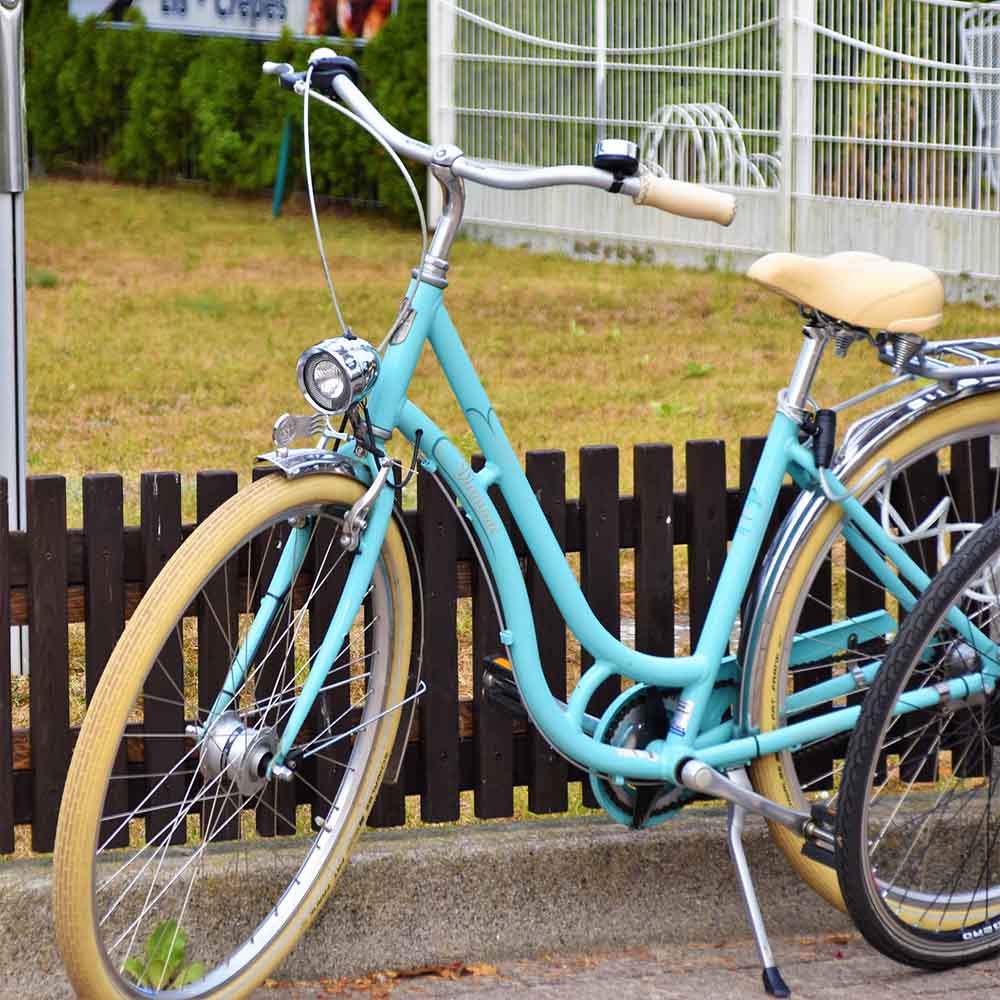 Mint-green step-through city bike with a front lamp, mudguards and cream-wall tyres