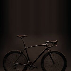 All-black road bike with drop handlebars and deep-section rims on a dark background